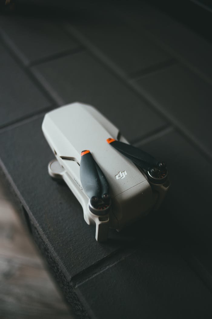 Close-up of a compact DJI drone resting on a dark surface with a soft lighting effect.